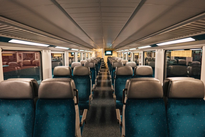 the inside of a train with multiple rows of empty chairs