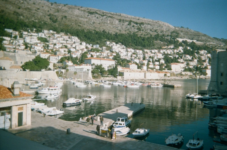 boats are docked at the dock with many houses in the distance