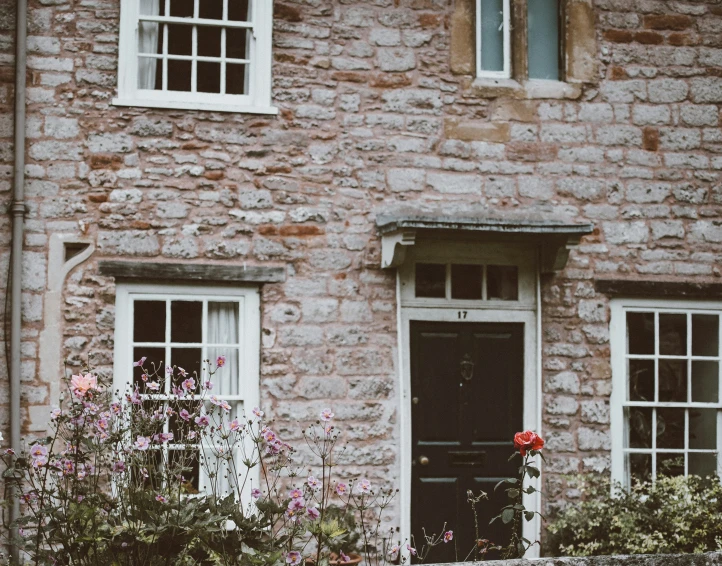 an old brick house with a black door and flower pot