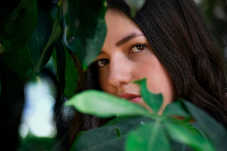 a woman is peeking through some leaves