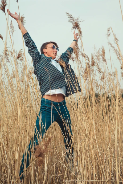 a woman is standing on top of a tall grass field