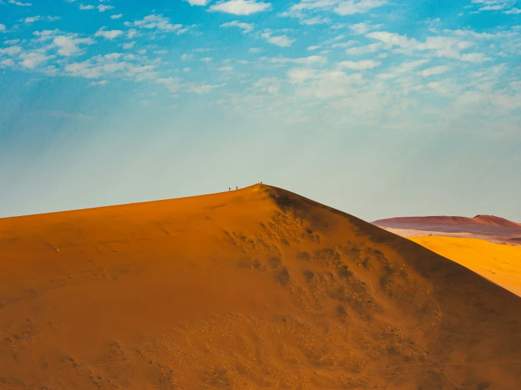 a person walking up a dune hill at sunset