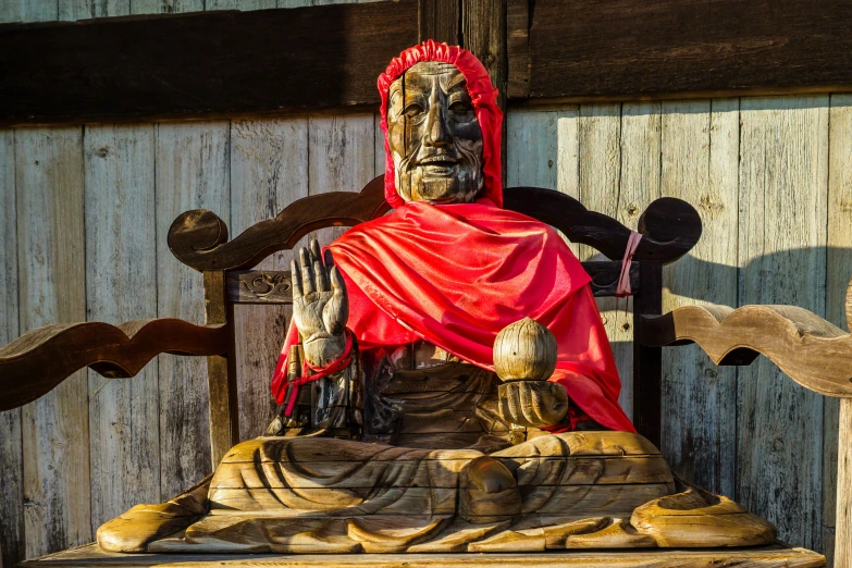 an old and worn statue of a person with a red scarf