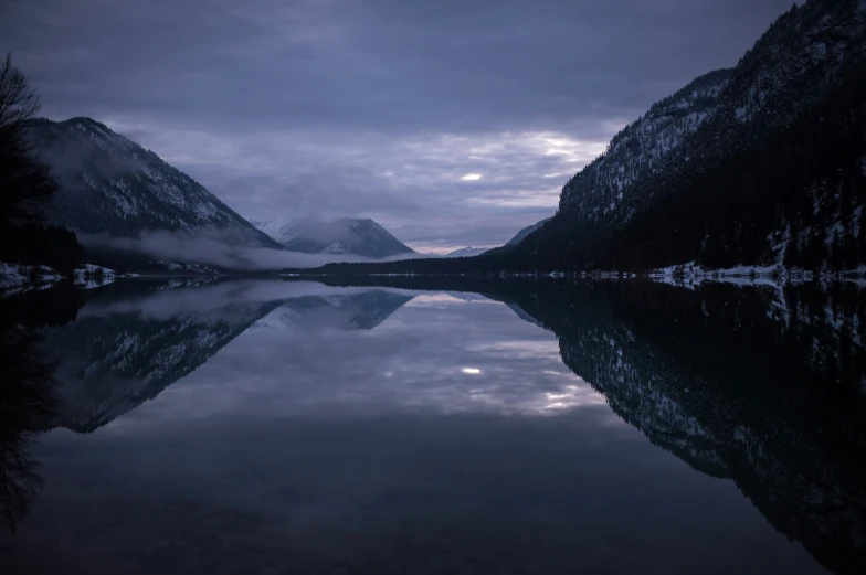 a lake in a mountains area is illuminated by lights