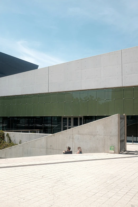 people sitting outside a concrete building under blue sky