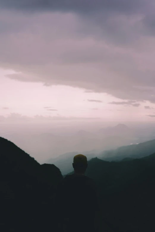 man standing on a rock overlooking mountains at night