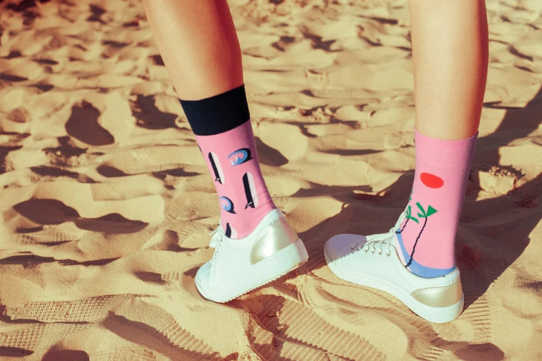 a person standing on the sand wearing socks with letters