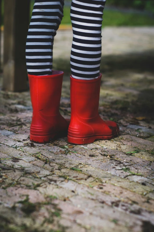 woman's legs wearing black and white  leggings with red rain boots