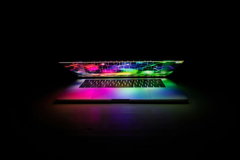 a laptop sits glowing in the dark on a surface