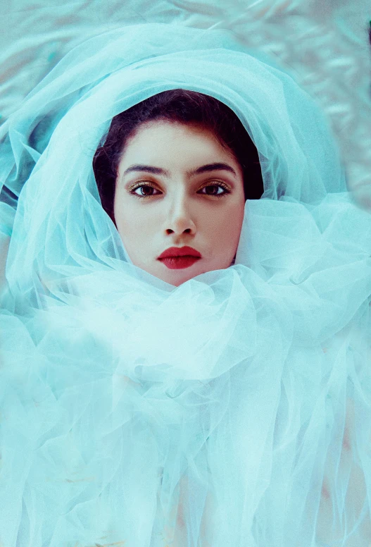 a woman is wearing a veil and sitting in the snow