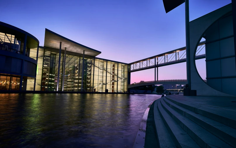 an illuminated building on a lake surrounded by buildings