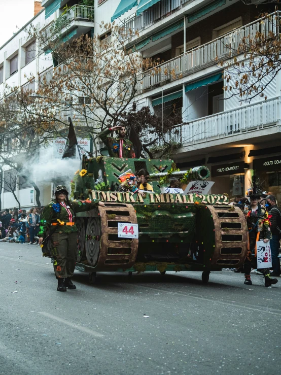 a group of people in a street parade with a military vehicle