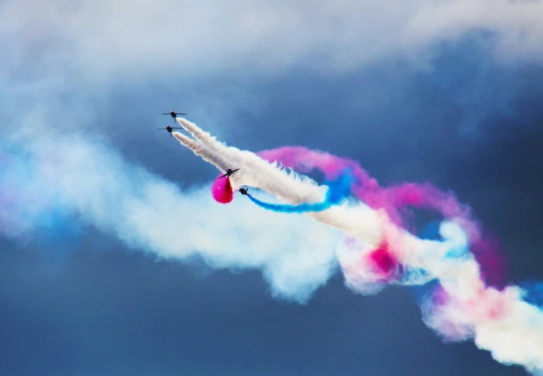 two planes flying in opposite directions with colorful smoke