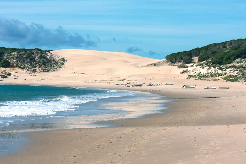 the ocean with beach chairs and sand dunes