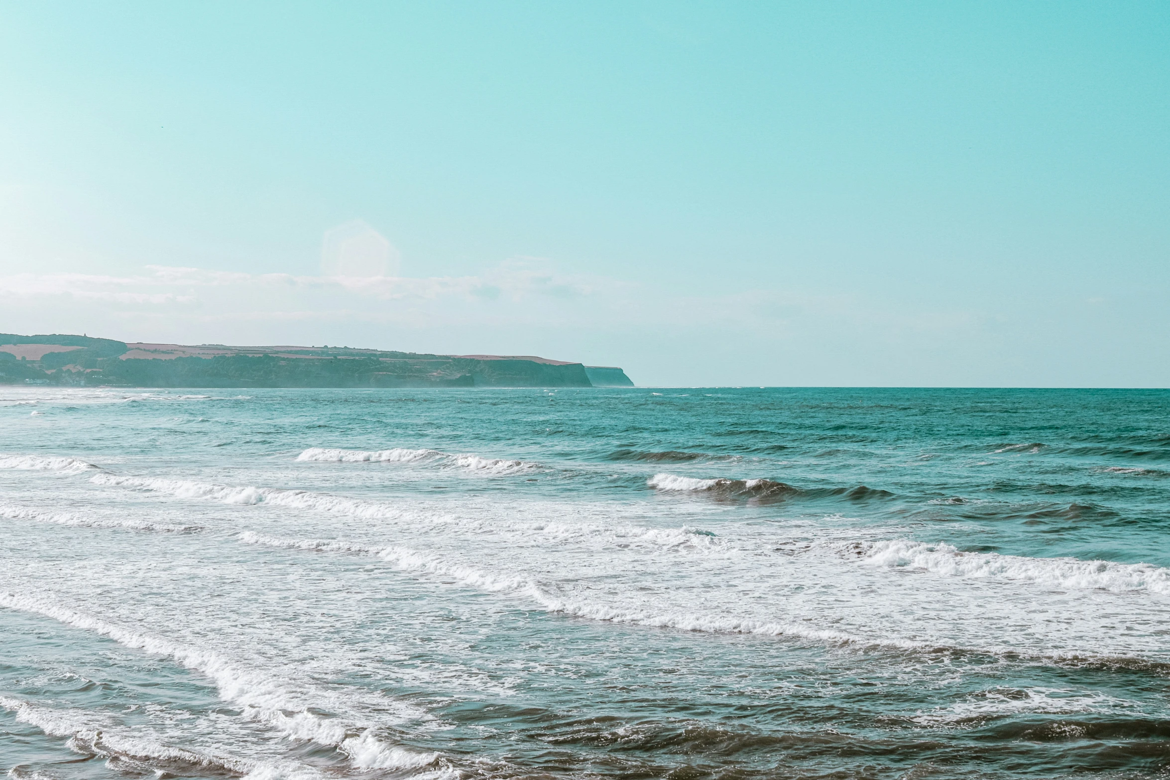 the waves on the ocean are crashing against the cliff