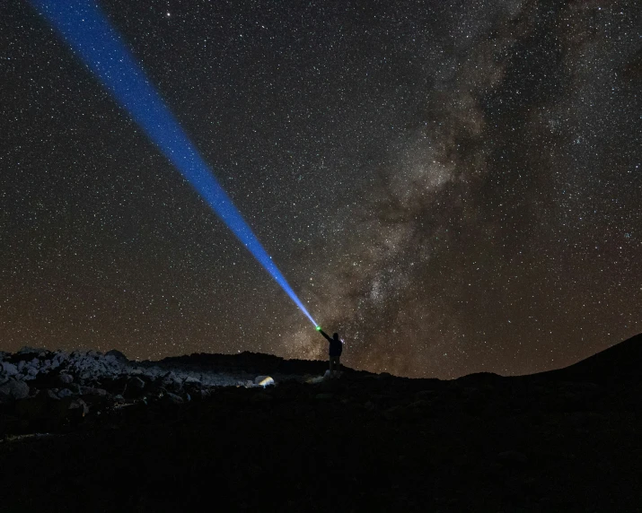 two people on the top of a hill look up at the stars