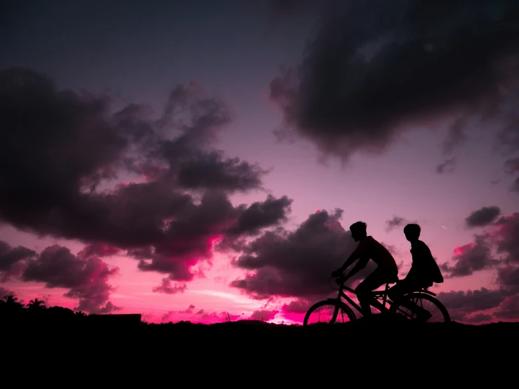 two people are riding their bikes in the sunset