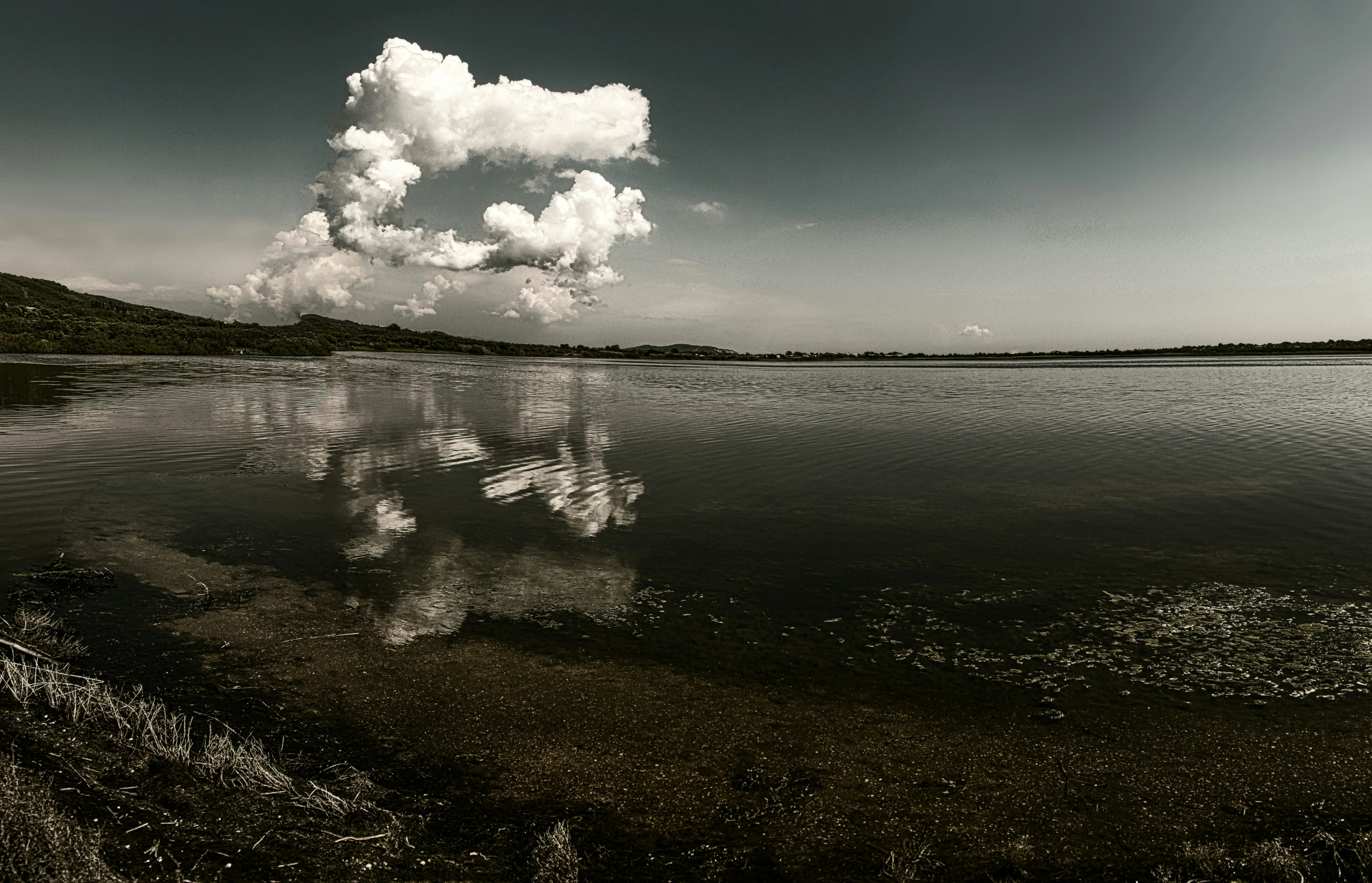 a large cloud that is floating over a lake