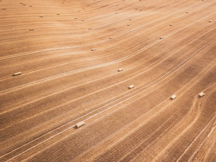 an aerial view of a dirt - covered field with some hay