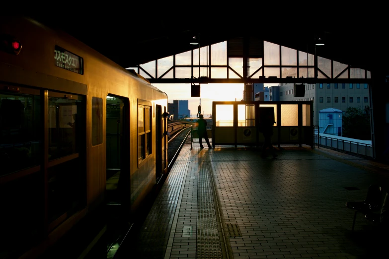 a train sitting at a train station with the sun setting