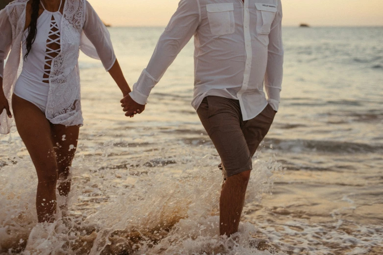 man and woman walking in the water holding hands