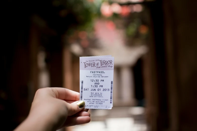 hand holding up white ticket for a movie