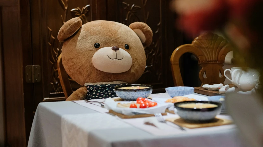 a stuffed bear sitting in front of cupcakes on a table