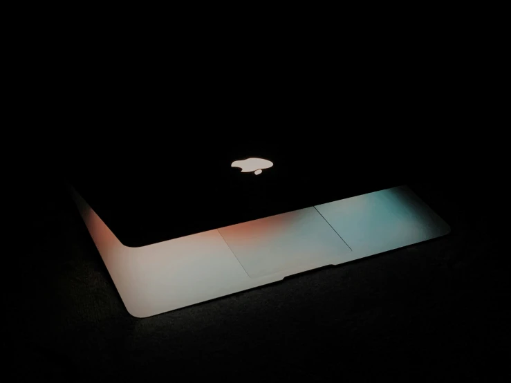 a mac computer sitting on top of a table in the dark