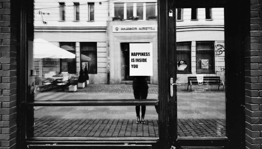 a woman standing in front of a store window holding a sign