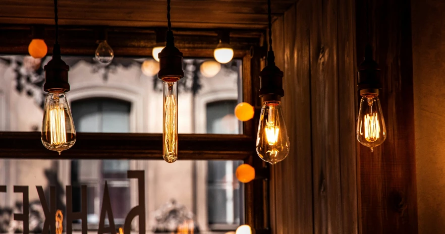 many light bulbs hanging from the ceiling with the building in the background