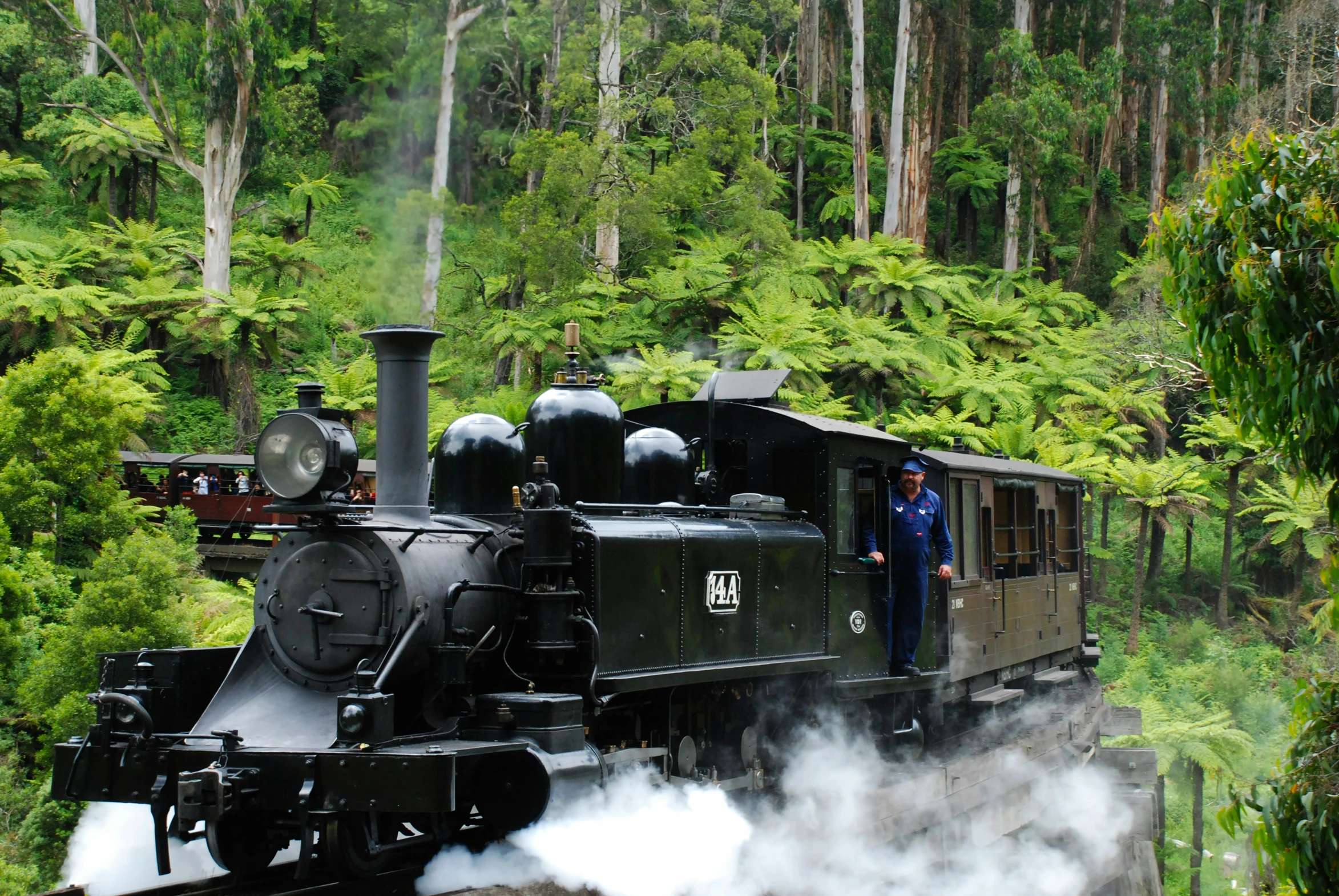 a man standing on a train engine with smoke coming out of it