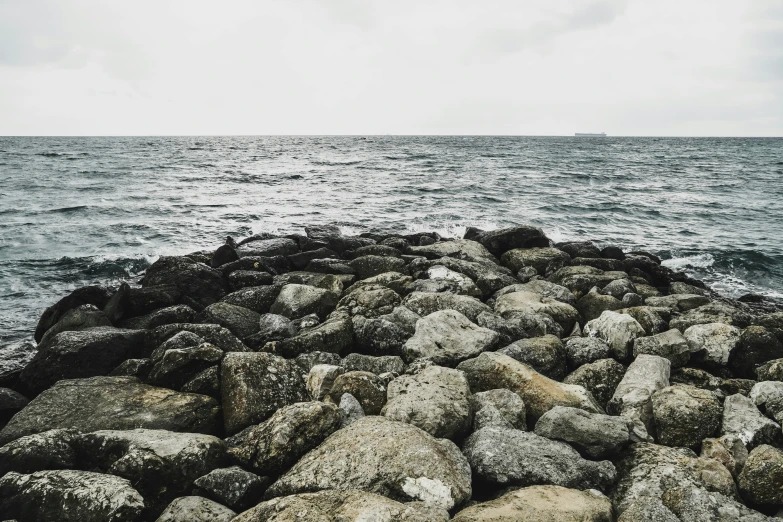 a group of rocks near the ocean with the water in the background