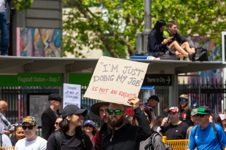 people with hats and sunglasses stand and hold signs