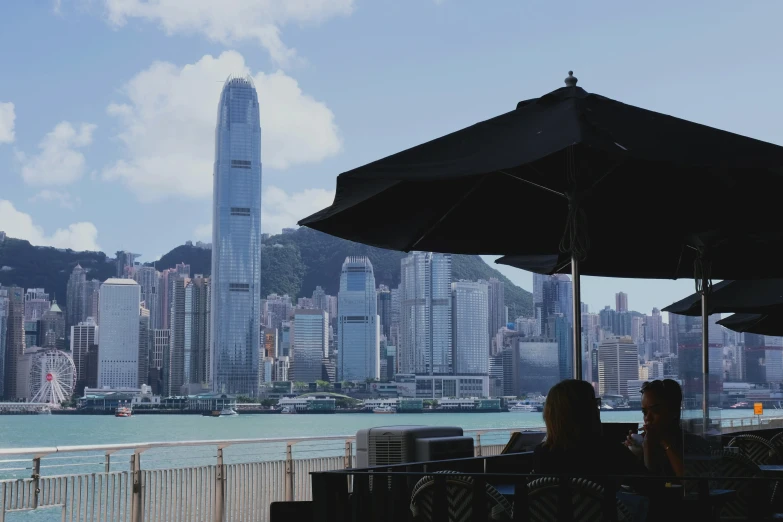 people are sitting under black umbrellas overlooking the ocean