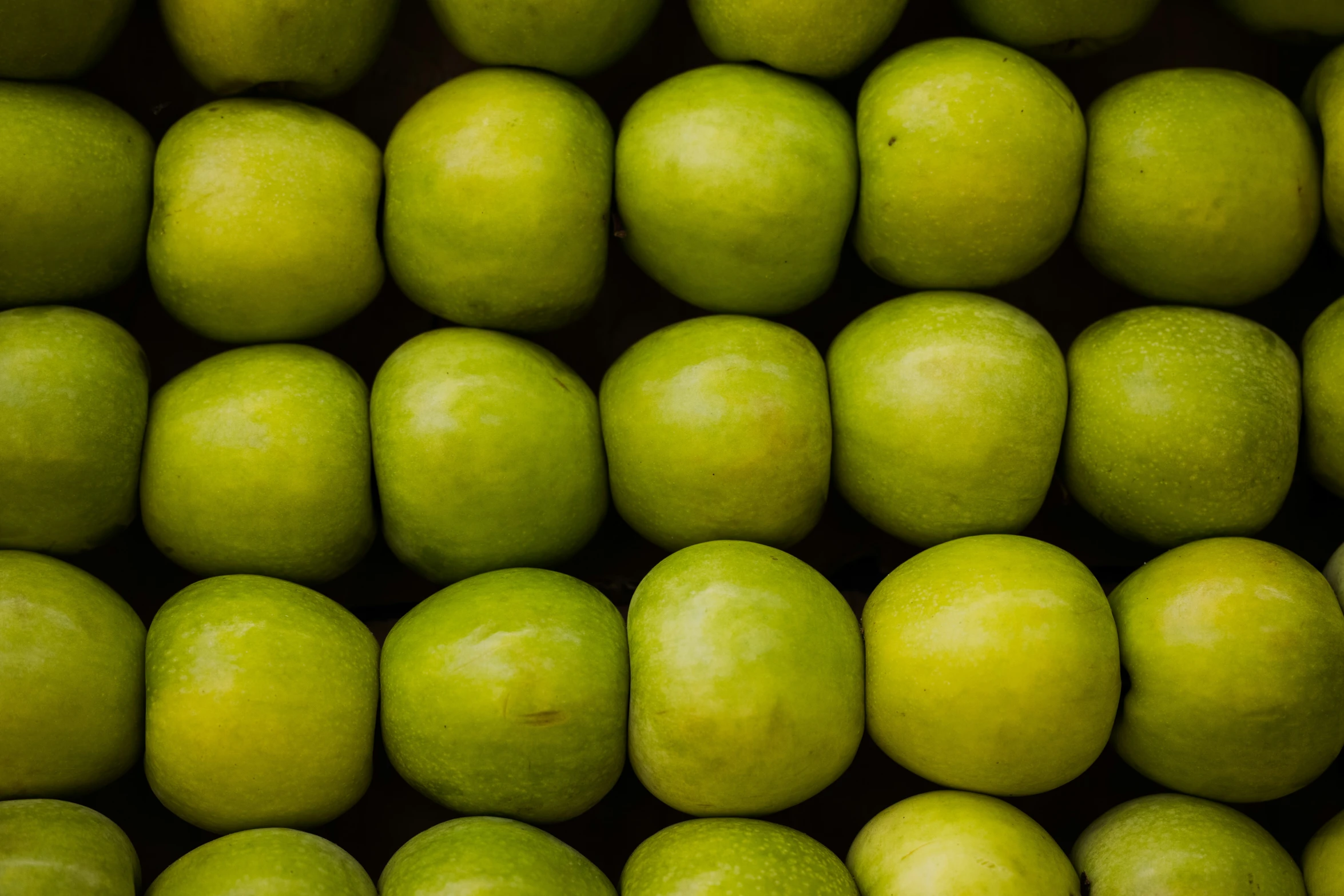 a bunch of green apples sitting next to each other