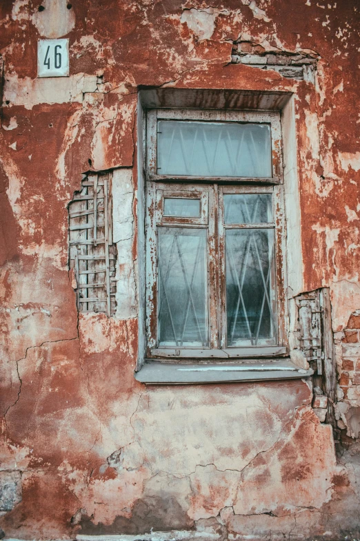 a rusted building with a broken window and number 46