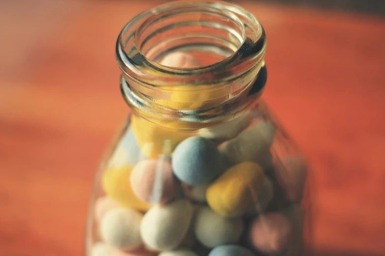 a jar with a couple tiny colorful candy candies inside