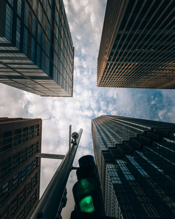 a stoplight next to tall buildings with sky background