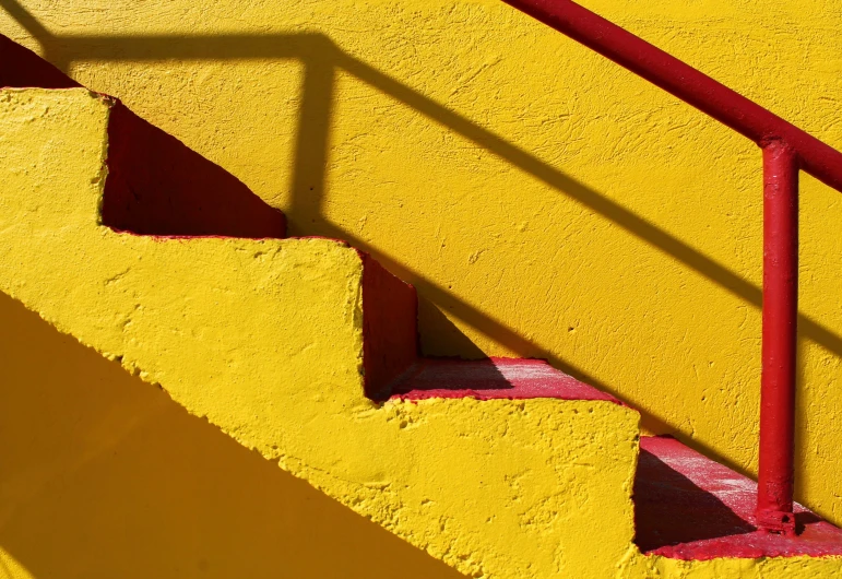 a set of stairs with red handrails and a yellow wall