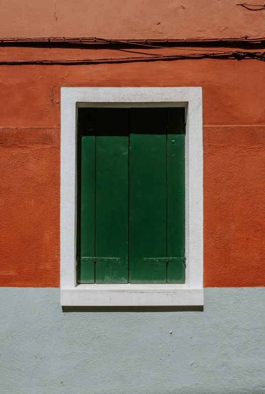 a small green window in an orange wall