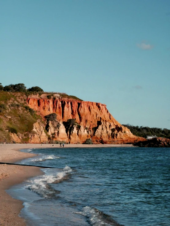 people walking on a beach near a mountain