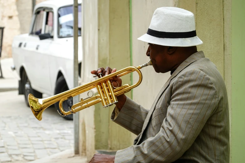 the man with his hat on is playing the trumpet