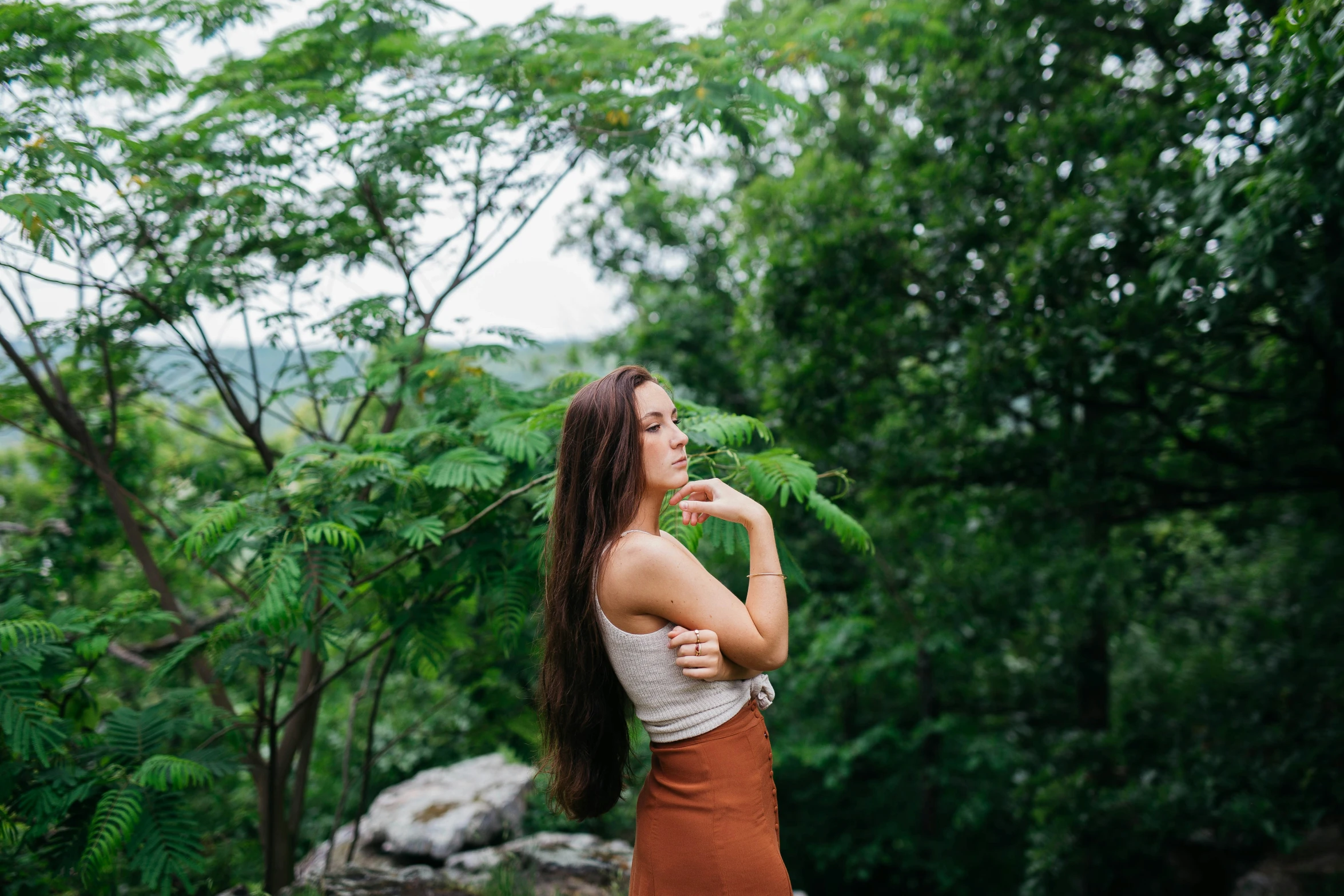 a young woman in the woods looking up into the sky