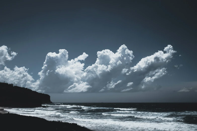 clouds hang over the water and an empty beach