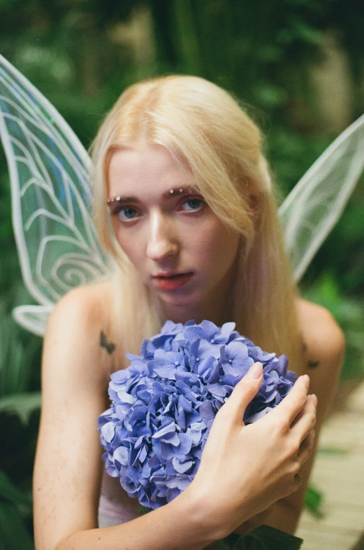 the fairy is holding a blue flower with a surprised face