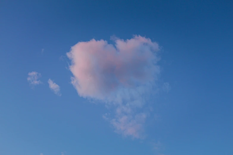 heart shaped cloud floating in blue sky against blue background