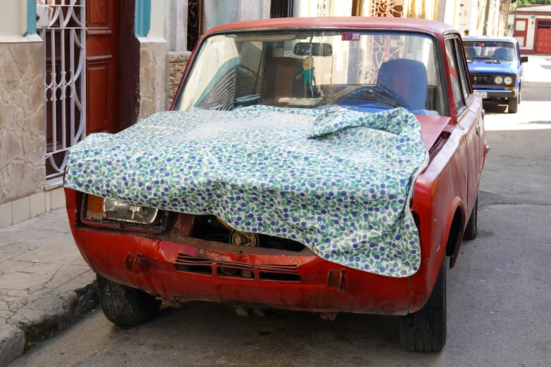a red car is covered in a blue fabric
