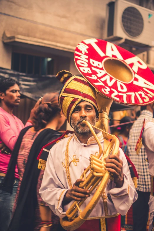 a man is wearing an elaborate red and gold hat while playing a trumpet