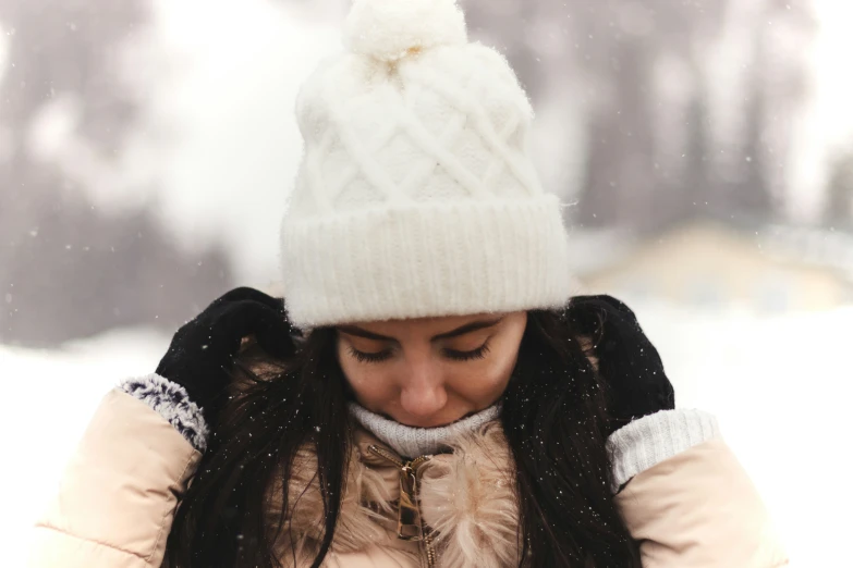 a woman with a snow hat looks down at her cell phone