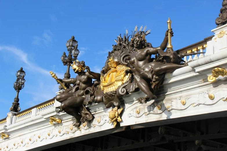statues on a white bridge with gold accents
